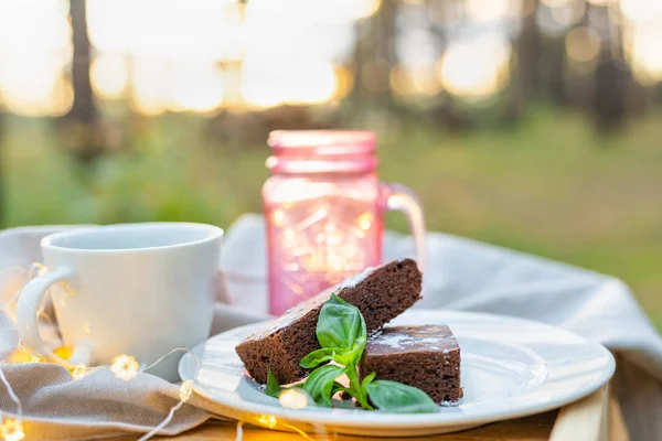Кофейная чашка с шоколадным тортом, украшенная мятой на открытом столе — стоковое фото