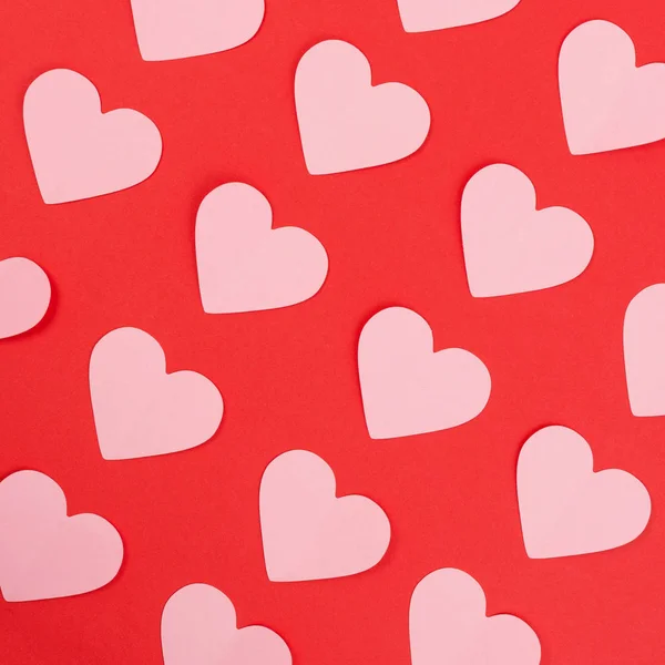 Pink paper hearts on red background — Stock Photo, Image