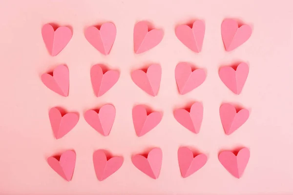 Pink paper hearts arranged in rows on pink background — Stock Photo, Image