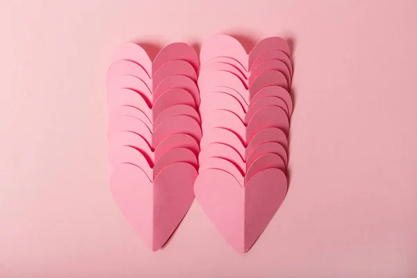 Montón de corazones de papel rosa sobre fondo rosa. Puesta plana — Foto de Stock