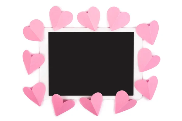 Corações de papel rosa emoldurando touchpad com tela em branco isolada em branco — Fotografia de Stock