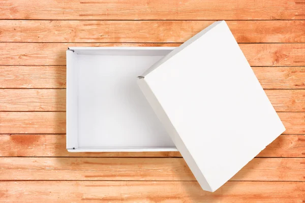 Opened white cardboard box on coral wooden background — Stock Photo, Image