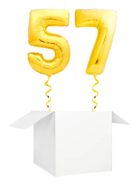 Golden number fifty seven inflatable balloon with golden ribbon flying out of blank white box isolated on white background — Stock Photo, Image