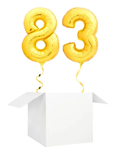 Golden number eighty three inflatable balloon with golden ribbon flying out of blank white box isolated on white background — Stock Photo, Image