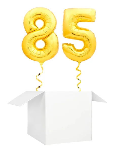 Golden number eighty five inflatable balloon with golden ribbon flying out of blank white box isolated on white background — Stock Photo, Image