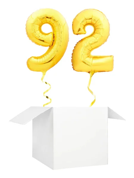 Número dorado noventa y dos globo inflable con la cinta dorada que vuela fuera de la caja blanca en blanco aislada sobre fondo blanco —  Fotos de Stock