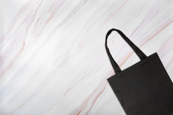 Svart shoppingväska på marmor bakgrund med naturliga mönster — Stockfoto