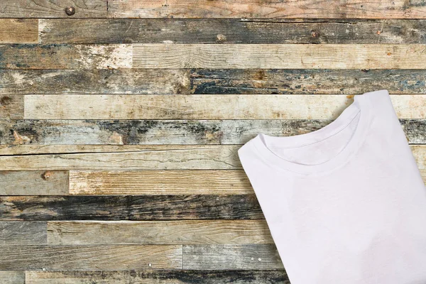 Camiseta plegada blanca en blanco sobre fondo de madera — Foto de Stock