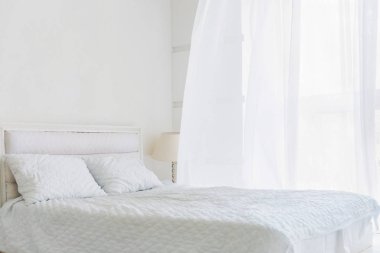Beyaz yatak, beyaz duvarlar ve beyaz perde ile pencere soyut Oda