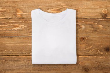 Beyaz t-shirt ahşap duvar arka plan üzerinde katlanmış. Düz yatıyordu