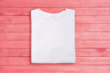 Beyaz görünümünü boş t-shirt pembe ahşap arka plan üzerinde katlanmış. Kadın tshirt tasarım şablonu
