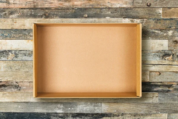 Flat lay of empty cardboard box on vintage wooden background — Stock Photo, Image