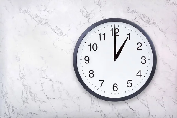Настенные часы показывают один час на текстуре белого мрамора. Часы в офисе показывают час дня или час ночи — стоковое фото