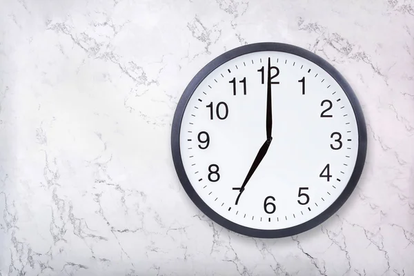 Wall clock show seven oclock on white marble texture. Office clock show 7pm or 7am — Stock Photo, Image