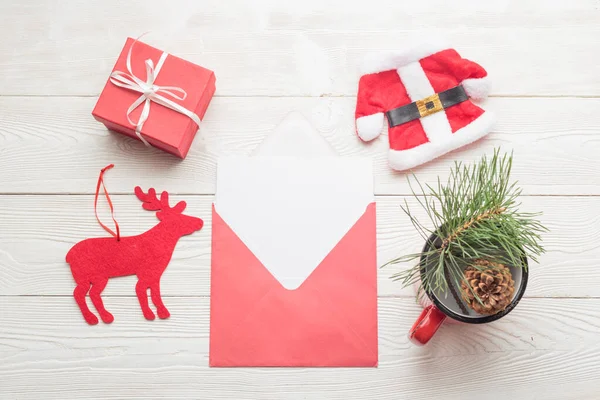 白い木製の背景にクリスマスオブジェクトと封筒に白い空白の紙のカード — ストック写真