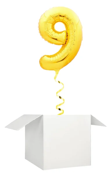 Золотой шарик номер девять, летящий из пустой белой коробки на белом фоне — стоковое фото