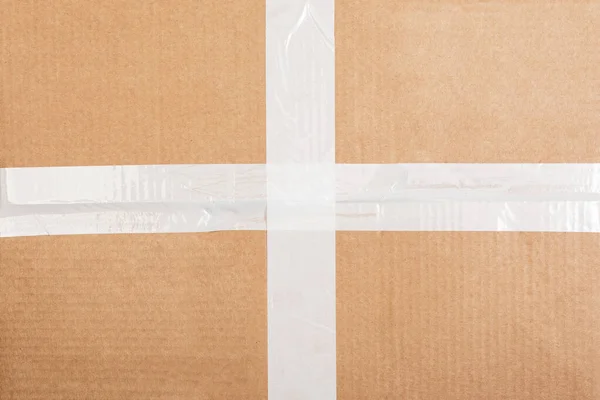 Картонный фон коробки с белой липкой лентой. Фон упаковки — стоковое фото