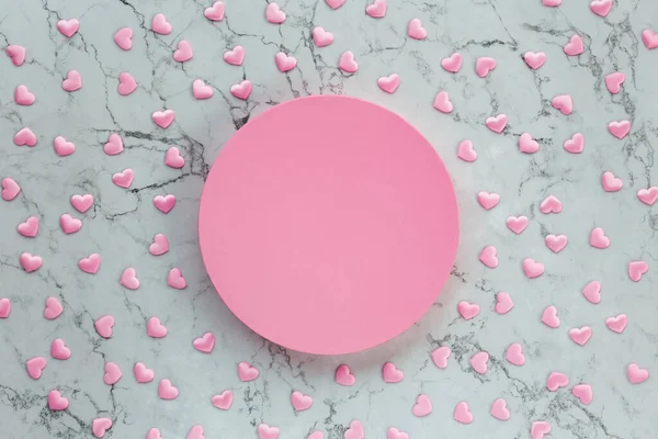 Kotak bundar merah muda pada latar belakang marmer dengan banyak hati kecil — Stok Foto