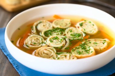 Geleneksel Alman Flaedlesuppe ve Avusturyalı Frittatensuppe consomme rulo veya çizgili chives, doğal ışık (seçici odak, odak çorba ortasında ile fotoğrafı ile süslenmiş krep ve gözleme dayalı)
