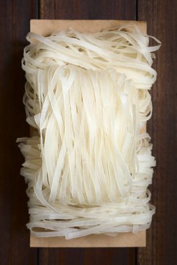 Çiğ pirinç unu şehriye, ek yükü üzerinde koyu renkli ahşap doğal ışık (seçici odak, odak üstünde erişte ile fotoğraflandı)