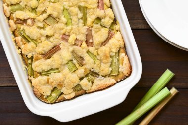 Taze pişmiş rhubarb parçalamak çanak, ek yükü üzerinde koyu renkli ahşap doğal ışık (seçici odak, odak pasta üstüne ile fotoğraflandı pişirme kek)