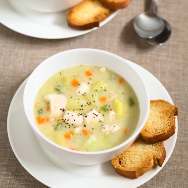 Tavuk ve patates çorbası çorba ekmek dilimleri tarafında, doğal ışık (seçici odak, odak çorba ortasında ile fotoğraflandı kase havuç ve yeşil biber ile)
