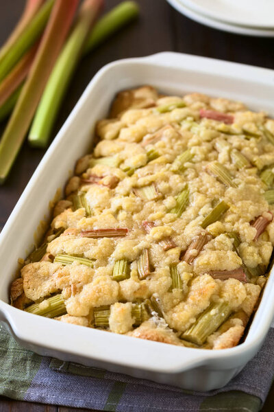 Freshly baked rhubarb crumble cake in baking dish, photographed with natural light (Selective Focus, Focus one third into the cake)