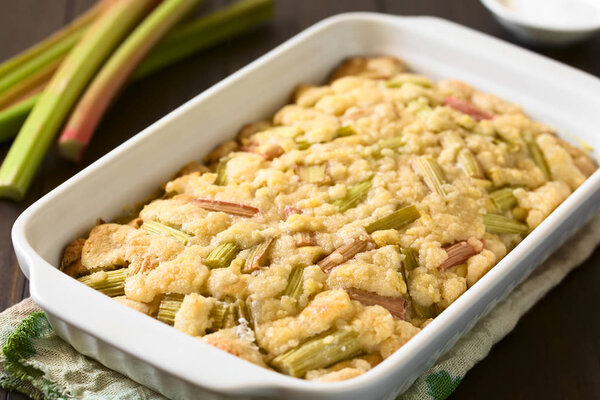 Freshly baked rhubarb crumble cake in baking dish, photographed with natural light (Selective Focus, Focus one third into the cake)
