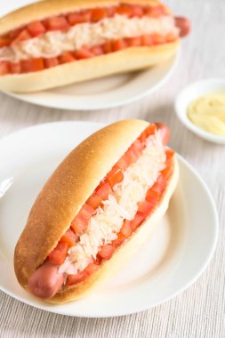 Şili Completo El Clasico (klasik) veya Completo Aleman (Almanca) geleneksel sosisli sandviç, yapılan ekmek, sosis, domates küpleri ve doğal ışık (seçici odak, odak üçte ilk hotdog haline ile fotoğraflandı lahana turşusu,)