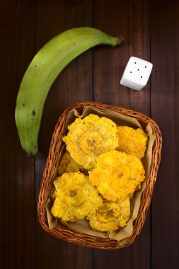 Patacon veya toston, kızarmış ve düzleştirilmiş adet yeşil plantain, geleneksel yiyecek ya da bir eşliğinde Karayipler, ek yükü doğal ışık ile karanlık ahşap üzerine fotoğrafı