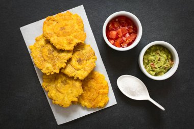 Patacon veya toston, kızarmış ve düzleştirilmiş adet yeşil plantain, geleneksel yiyecek ya da bir eşliğinde Caribbean, guacamole, domates ve soğan salatası, tarafında, tuz ek yükü üzerinde barut doğal ışık ile fotoğrafı