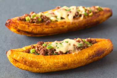 Kıyma, zeytin, yeşil biber ve soğan, üzerine, peynir ile doldurulmuş fırında olgun muz serpilir chives ile Orta Amerika'da Canoa de Platano (muz Kano), barut doğal ışık ile fotoğraflandı denilen geleneksel bir yemek