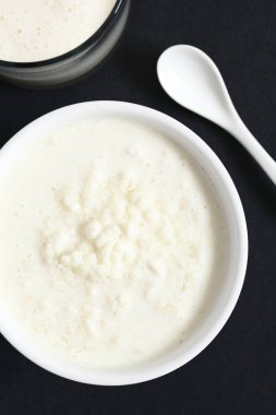 Tarafında, ek yükü barut doğal ışık (seçici odak, odak üstünde kefir taneleri ve kefir içmek ile fotoğraflandı kefir taneleri ile taze kefir bir bardak süt iç)