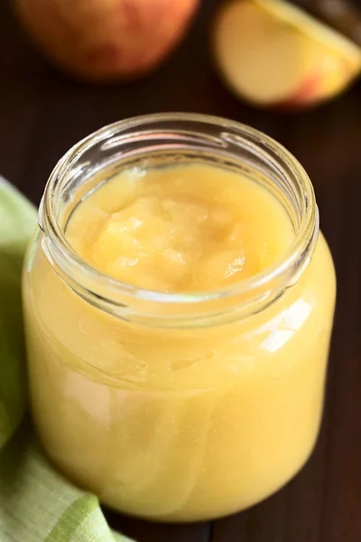 Fresh homemade apple sauce in glass jar, photographed with natural light (Selective Focus, Focus one third into the apple sauce in the jar)