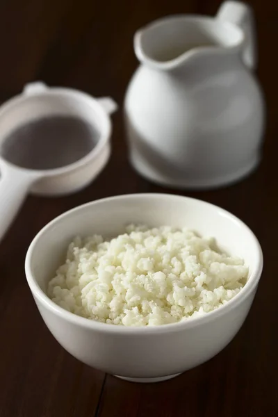 Kefir grains in bowl, strainer and milk in the back, photographed with natural light (Selective Focus, Focus one third into the kefir grains)