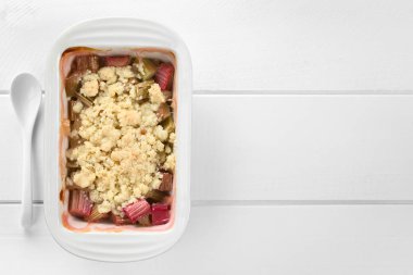 Ev yapımı ravent crumble veya güveç çanak net, Beyaz ahşap üzerinde havai fotoğraflanmış (seçici odak, tatlı üstüne odaklanmak)