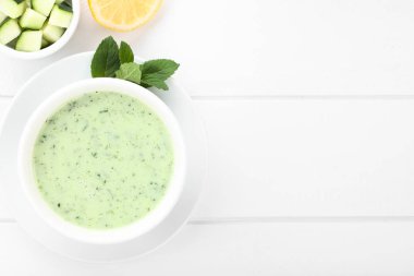 Ferahlatıcı soğuk salatalık, yoğurt, nane ve limon çorbası kasede, beyaz ahşap üzerinde havai fotoğraflandı (Seçici Odak, çorba odaklanın)