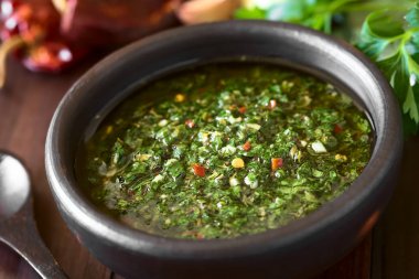 Çiğ Arjantin yeşil Chimichurri ya da Chimmichurri salsası ya da maydanoz, sarımsak, kekik, acı biber, zeytinyağı, sirke, kırsal kasede servis edilen, doğal ışıkla fotoğraflanmış (Seçici Odaklanma, resmin ortasında odaklan))