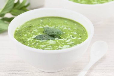 Taze ev yapımı krem yeşil bezelye ve kase de nane çorbası, taze nane yaprakları ile süslenmiş (Seçici Odak, Odak görüntünün ortasında)