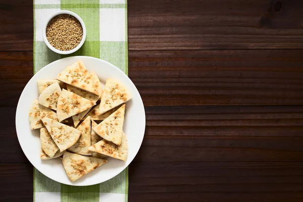 Homemade crispy pita chips with roasted sesame seeds and sea salt, photographed overhead with natural light