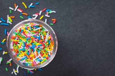 Cam kavanozda renkli şeker serpilir, kayrak üzerinde havai fotoğraflandı (Seçici Odak, kavanozda sprinkles odaklanın)