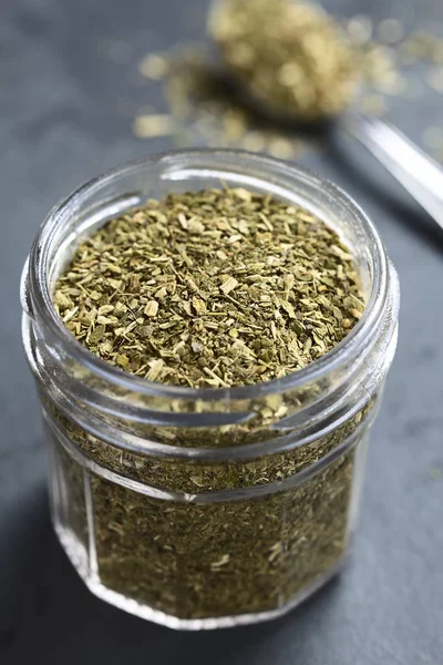Dried leaves of yerba mate tea, a traditional tea in South-America, photographed in glass jar on slate (Selective Focus, Focus one third into the tea leaves)
