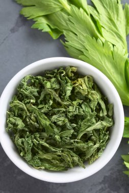 Kurutulmuş kereviz yaprakları çorba ve biftek içinde baharat olarak kullanılmak üzere, arduvaz üzerinde havai fotoğraflanmış (seçici odak, üst kereviz yaprakları odaklanmak) 