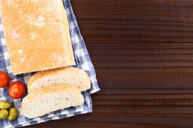 Taze İtalyan ciabatta ekmek dilimlenmiş, kiraz domates ve yeşil zeytin tarafında, koyu ahşap (Seçici Odak, ekmek üstüne odaklanın tepede havai fotoğraflandı)