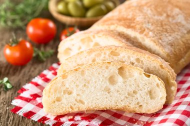 Taze İtalyan ciabatta ekmeği dilimlenmiş, kiraz domatesleri ve yanında yeşil zeytinler (Seçici Odaklanma, ilk dilime odaklan)