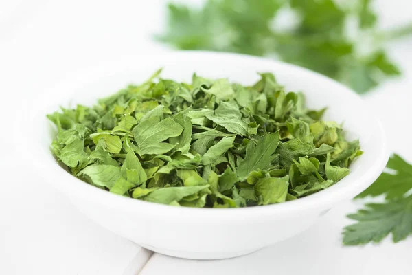 Dried parsley leaves in small bowl (Selective Focus, Focus in the middle of the image)