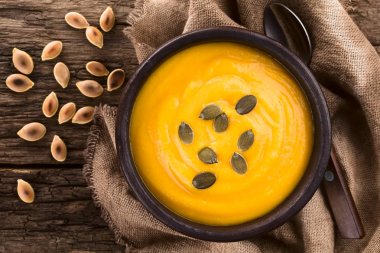 Taze ev yapımı kabak mus veya krem rustik kase üzerinde kavrulmuş pepita kabak çekirdeği ile, rustik ahşap (Seçici Odak, Tatlı üstüne odaklanın tepede havai fotoğraflandı)