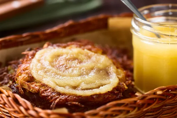 Fresh homemade thin potato fritters or pancakes with apple sauce in basket, a traditional German snack or dish called Kartoffelpuffer or Reibekuchen (Selective Focus, Focus one third into the apple sauce on the fritter)