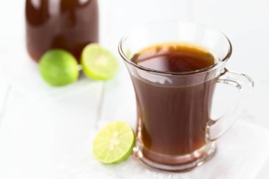 Fresh homemade Aguapanela, Agua de Panela or Aguadulce, a popular Latin American sweet drink made of panela unrefined whole cane sugar boiled in water, served warm or cold with lime (Selective Focus, Focus on the front of the glass rim) clipart