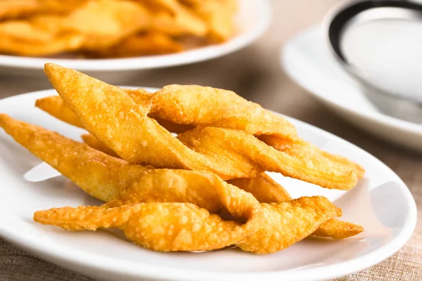 Fresh homemade crispy deep-fried angel wing or bowtie cookies, traditional biscuits in many European countries (Selective Focus, Focus on the front edge of the top cookie)